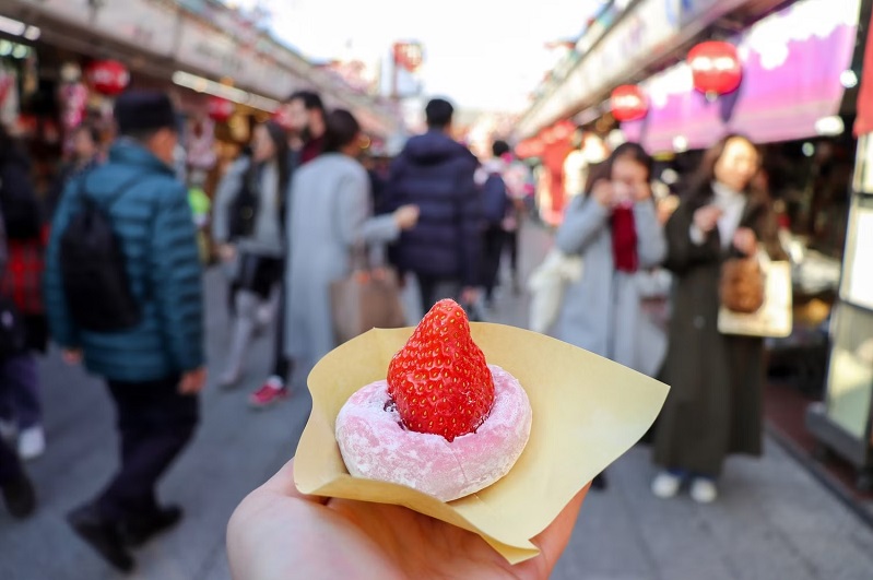 Một du khách cầm chiếc bánh ngọt thơm ngon mà họ mua được ở quận Asakusa của thành phố Taito, Tokyo, Nhật Bản