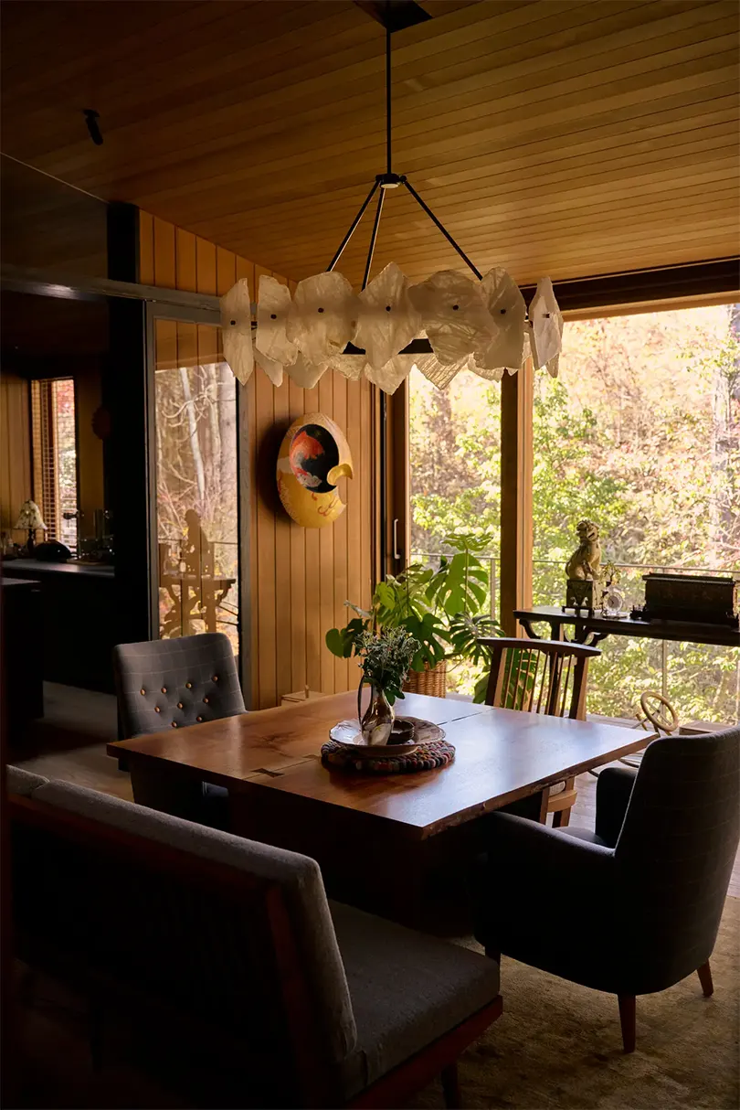 Trong phòng ăn, mặt dây chuyền Christopher Boots trên bàn và ghế sofa tựa lưng của George Nakashima và một cặp ghế bành Hemmakväll cổ điển của Carl Malmsten