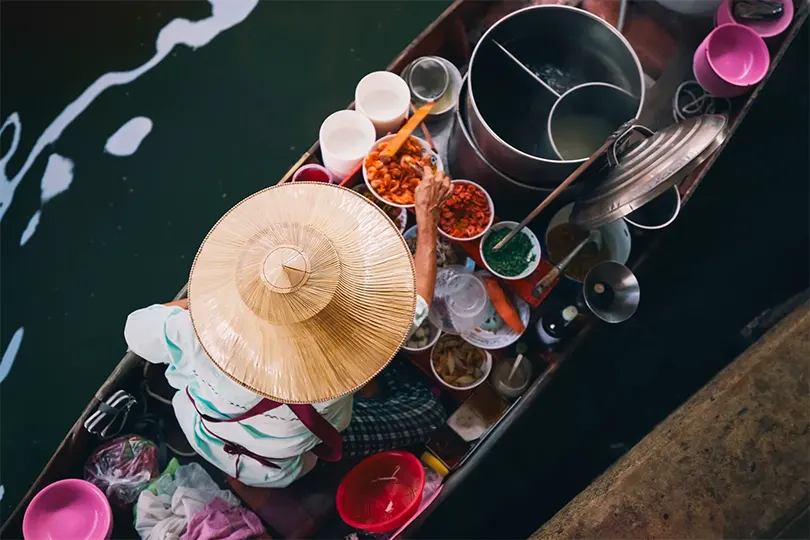 Một người phụ nữ đang chế biến đồ ăn trên mặt nước ở Damnoen Saduak gần Bangkok.