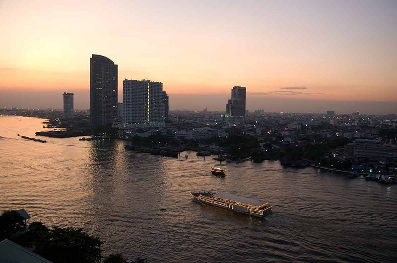 Quang cảnh sông Chao Praya ở Bangkok vào ban đêm, với những chiếc thuyền và sà lan trên sông.