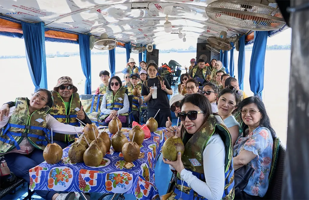 Khách vui vẻ uống nước dừa tươi và ngắm sông Mekong