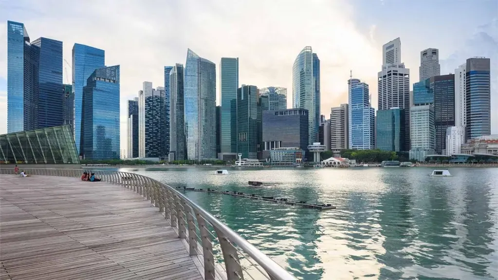 Marina Bay Waterfront Promenade với đường đi bộ lát ván gỗ, một bên là mặt nước với đường chân trời Singapore